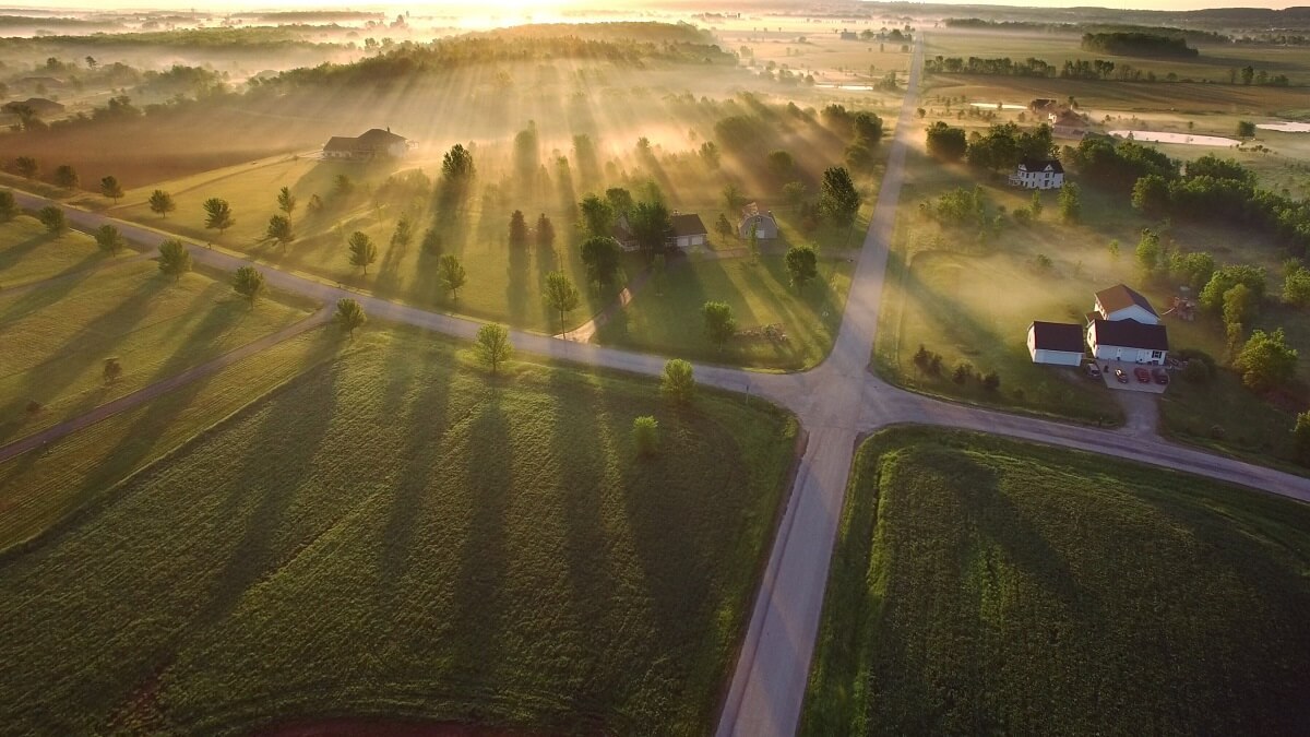 Aerial view of farm properties with a radiant sunrise.