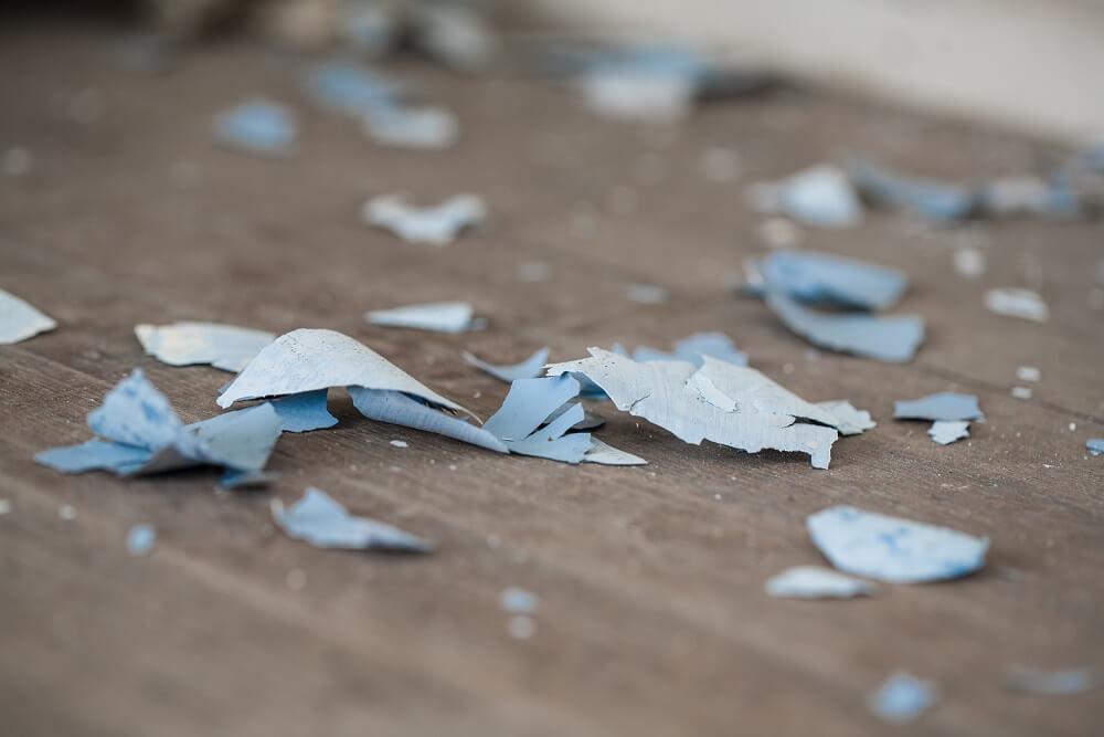 Paint peels on the floor of a home.