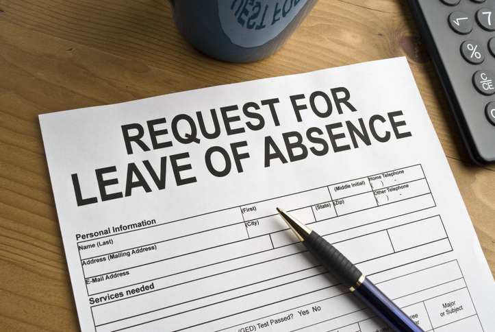 A 'Request for Leave of Absence' form on a wooden desk, with a pen on top, next to a mug and a phone.