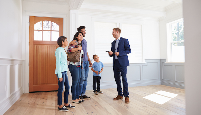 A real estate agent showing a family a brightly lit home.