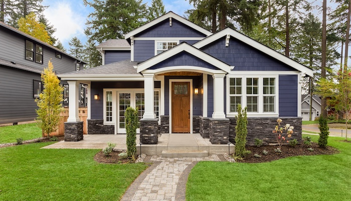 Exterior of a nice house with blue vinyl and a wood door.